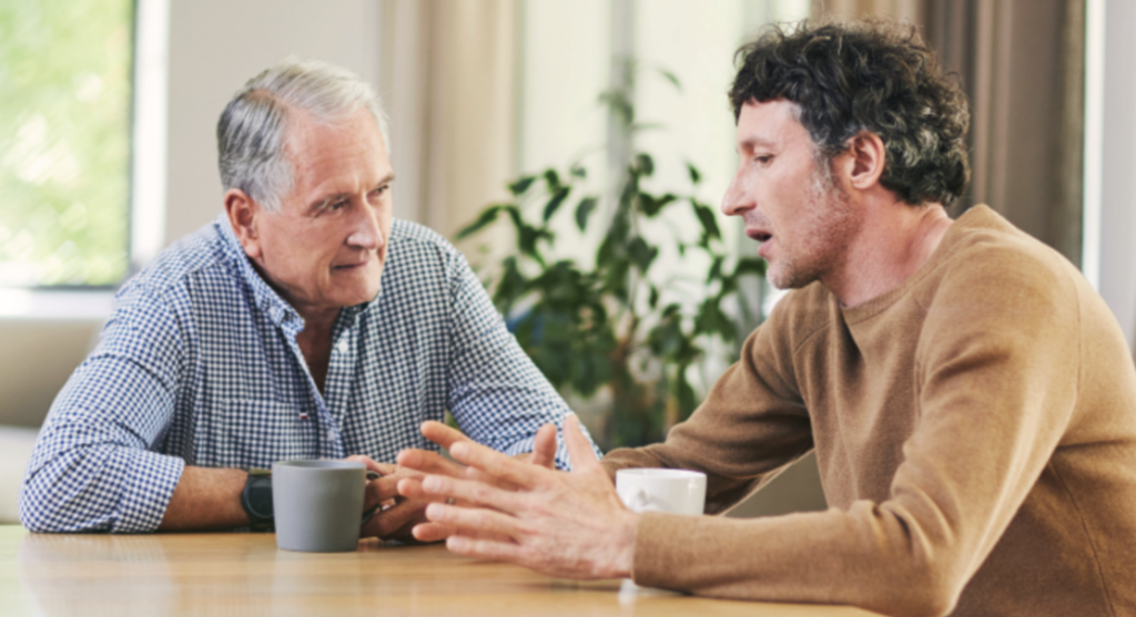 Senior Man Sitting Down And Talking To His Son