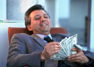 Can You Trust Private Equity Owned Hospitals And Healthcare Providers? &Raquo; Photo Of A Smiling Man In A Business Suit Leaning Back In A Chair With A Handful Of Cash Canva 1 300X214 1