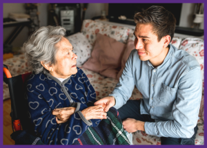 Care Homes For Dementia Patients: When Is It The Right Time? &Raquo; Photo Of A Young Man Sitting With His Grandmother Holding Her Hand While She Sits In A Wheelchair Canva With Border Added 1 300X214 1