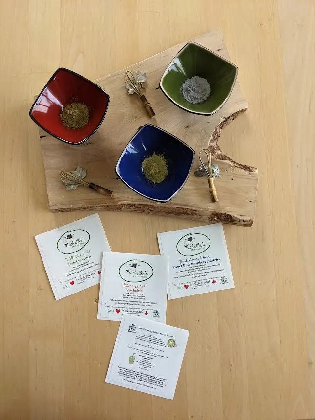 Three Matcha Powders In Small Dishes With Whisks, And Labels