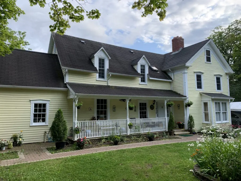 Historical House With Upstairs And Front Porch, Big Tress, And Creek On The Side Of The House