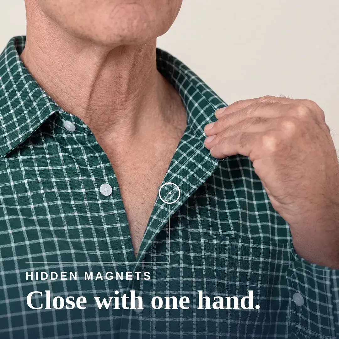 Close-Up Of A Man Wearing A Green And White Plaid Button-Up Shirt, Pulling The Collar Slightly With His Right Hand. A Small Inset Circle Highlights A Hidden Magnetic Area At The Collar. | Tailored-Fit#Green Check