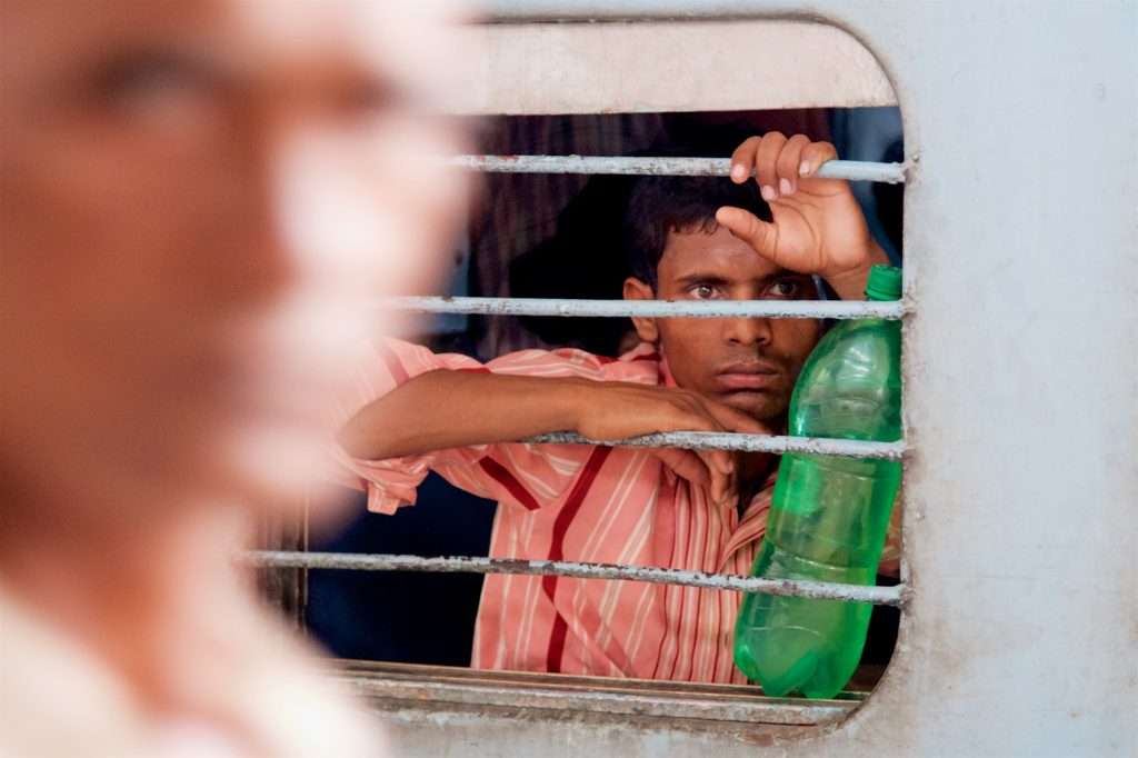 Man With Green Water Bottle On Train At Delhi Train Station In India By Ralph Velasco