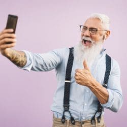 Senior man using mobile smartphone and listening music with airpods - Happy man having fun with new trends technology social media apps - Elderly lifestyle.