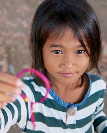 The Art Of Meaningful Souvenir Collecting: Travel Keepsakes For Gen X And Baby Boomer Explorers &Raquo; Little Girl Holding Pink Bracelet Battambang Cambodia Copyright 2013 Ralph Velasco