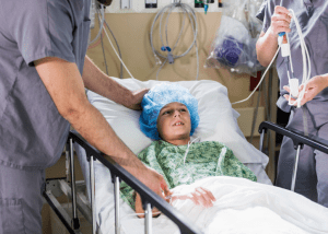 Preparing For Your Child’s Surgery &Raquo; Photo Of A Young Boy Lying In A Hospital Bed After Surgery With 2 Doctors By His Side Checking On Him Canva 1 300X214 1