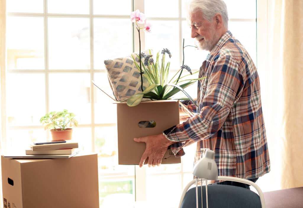 Senior Man Carrying Boxes At Home