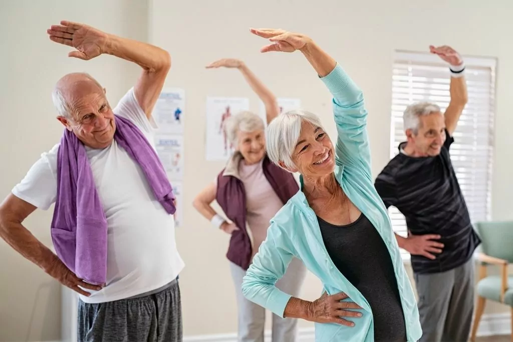 Group Of Four Seniors Stretching Together 