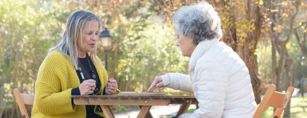 Senior Woman Playing Memory Game Outside With Her Daughter