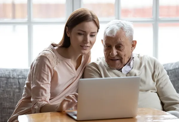 Woman Helping Senior Man With Laptop