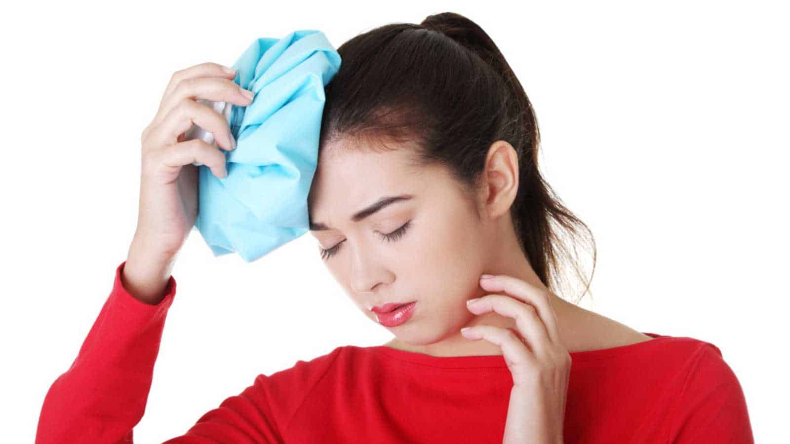 Woman With Ice Bag For Headaches And Migraines , Isolated On White
