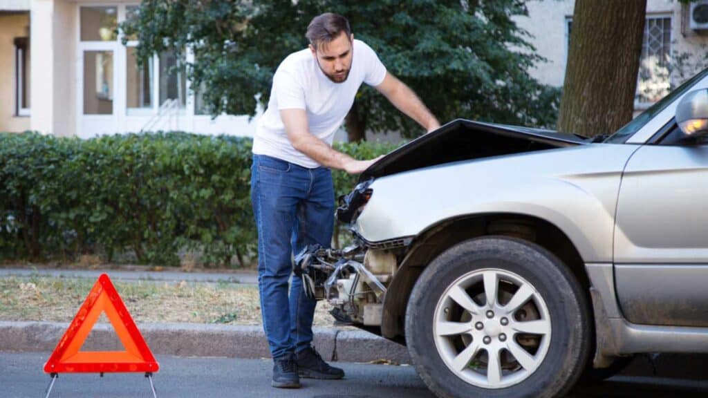 Driver Man Looking On Wrecked Car In Car Accident. Man Regrets About Fixing Car After Auto Crash.