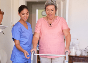 Tips For Managing Parkinson’s Disease &Raquo; Photo Of An Aide Helping A Middle Aged Woman Walk With A Walker Canva 1 300X214 1