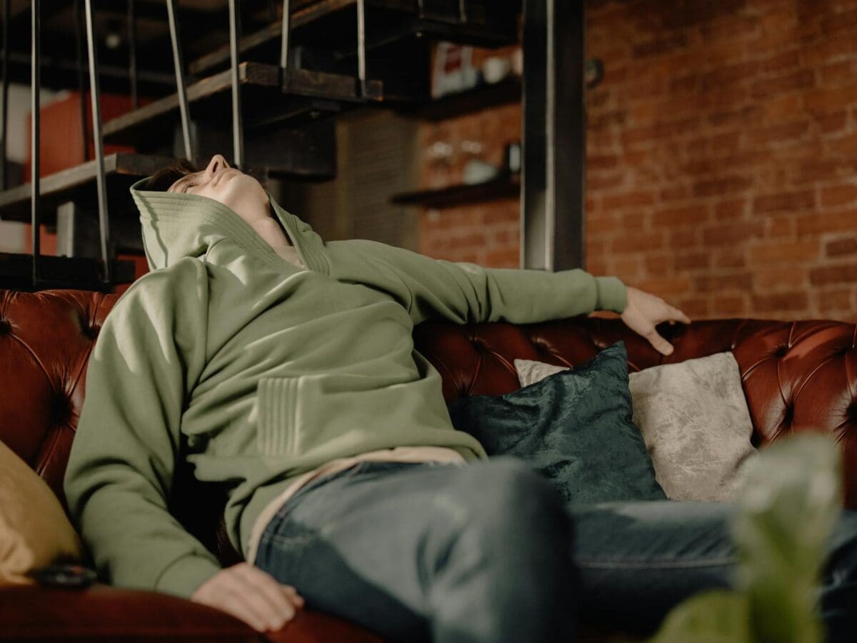 Man In Gray Jacket Sitting On Green Couch