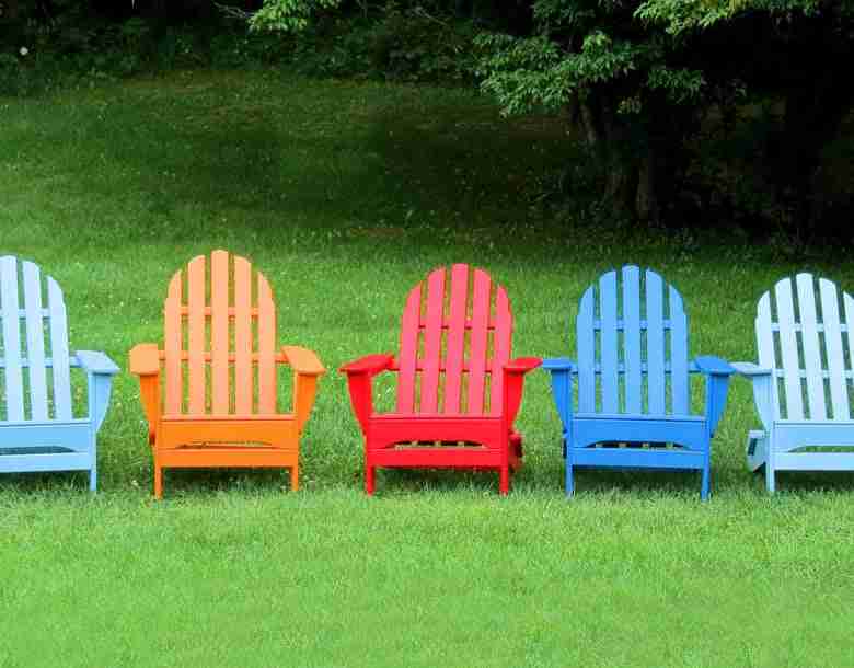 Different Colored Lawn Chairs On A Green Lawn. 